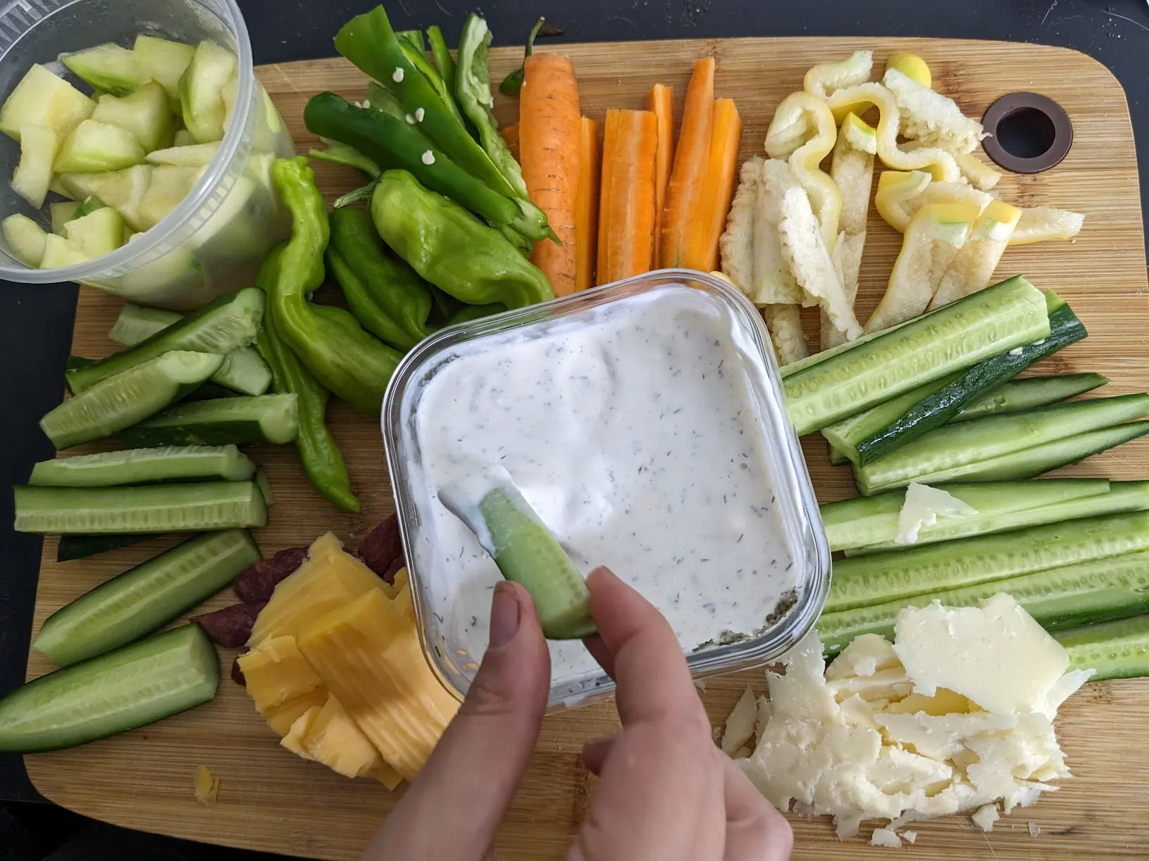 Someone dipping a vegetable on a grazing board